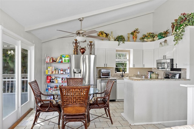 kitchen with white cabinetry, vaulted ceiling with beams, tasteful backsplash, and appliances with stainless steel finishes