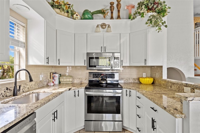 kitchen featuring sink, stainless steel appliances, light stone countertops, white cabinets, and decorative backsplash