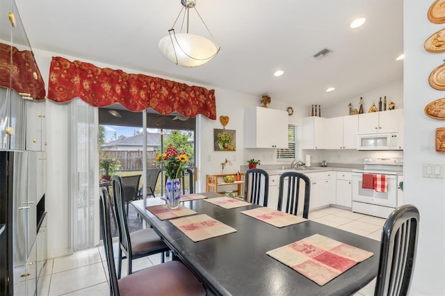 dining area featuring sink, vaulted ceiling, and light tile patterned floors