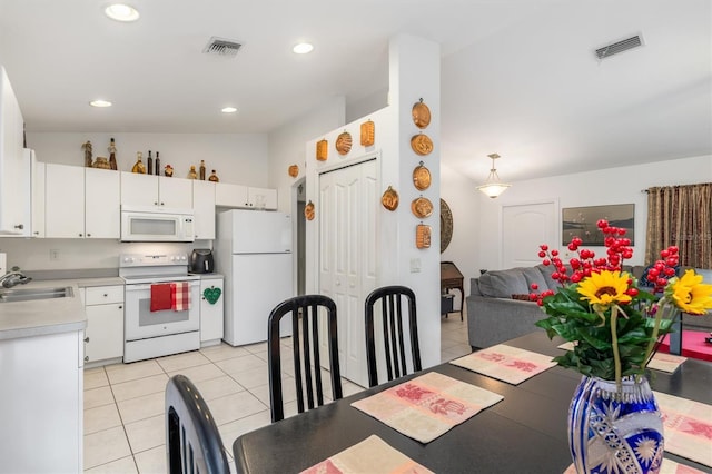 kitchen featuring lofted ceiling, sink, white appliances, white cabinets, and light tile patterned flooring