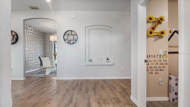 corridor featuring a notable chandelier and light hardwood / wood-style flooring