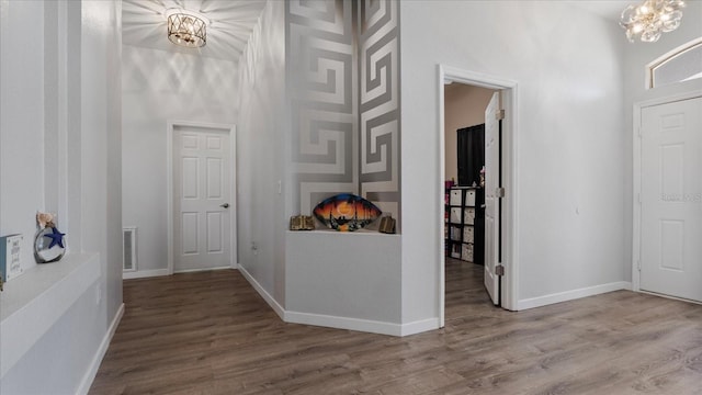 foyer entrance featuring hardwood / wood-style floors, an inviting chandelier, and a towering ceiling