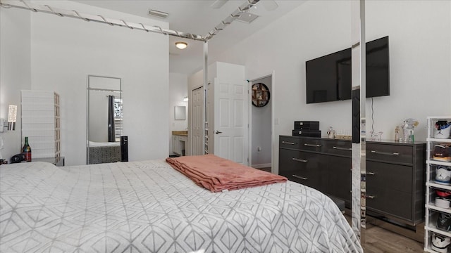 bedroom with ensuite bath and wood-type flooring