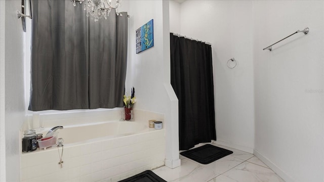 bathroom with tiled bath and a chandelier