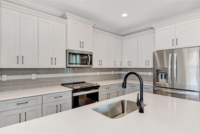 kitchen with sink, appliances with stainless steel finishes, tasteful backsplash, light stone countertops, and white cabinets