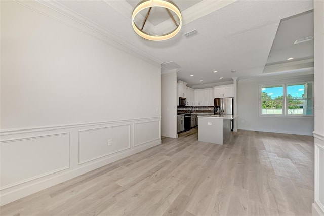 unfurnished living room with ornamental molding, light hardwood / wood-style floors, and a tray ceiling