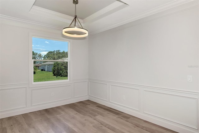 empty room featuring a raised ceiling, crown molding, and light hardwood / wood-style flooring