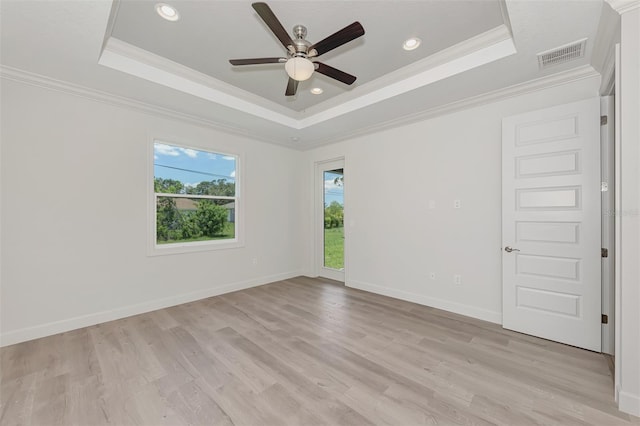 empty room with ornamental molding, light hardwood / wood-style floors, a raised ceiling, and ceiling fan