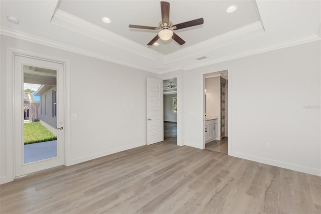 unfurnished bedroom with a raised ceiling, ensuite bath, ceiling fan, and light hardwood / wood-style flooring