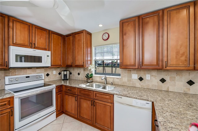 kitchen with tasteful backsplash, sink, white appliances, and light stone counters