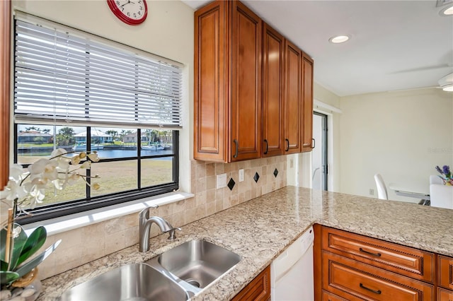 kitchen featuring white dishwasher, sink, a wealth of natural light, and a water view