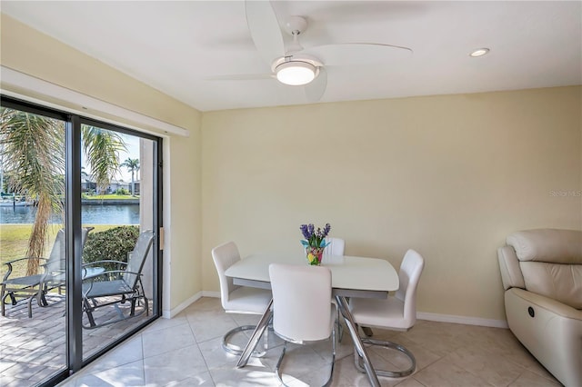 dining area featuring light tile patterned flooring, a water view, and ceiling fan