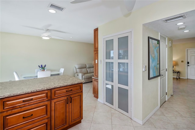 kitchen featuring light stone counters, ceiling fan, and light tile patterned floors