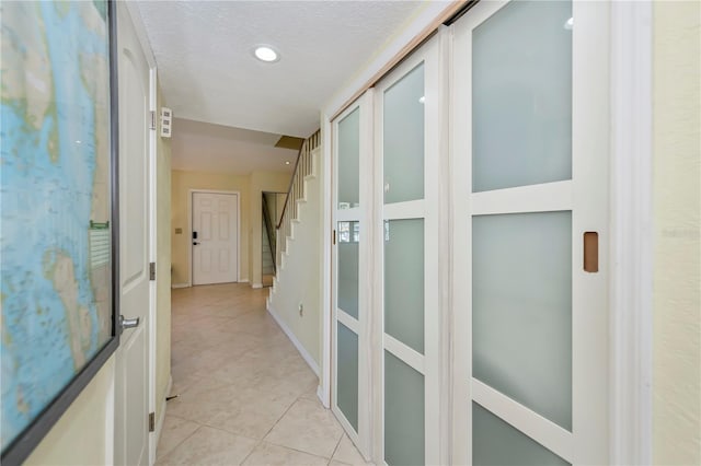 corridor with a textured ceiling and light tile patterned floors