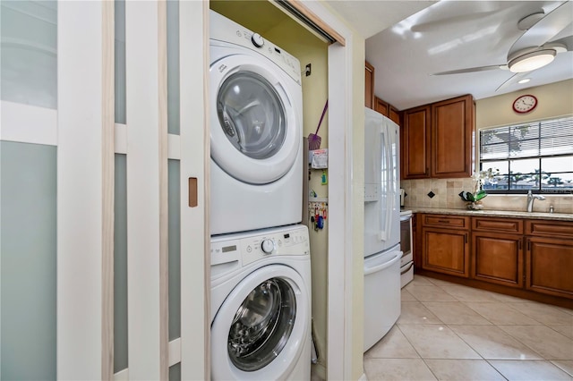 clothes washing area with sink, stacked washer / drying machine, light tile patterned floors, and ceiling fan