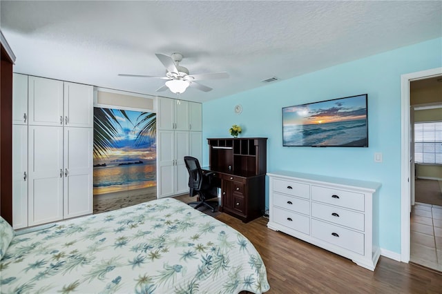 bedroom featuring ceiling fan, dark hardwood / wood-style floors, and a textured ceiling