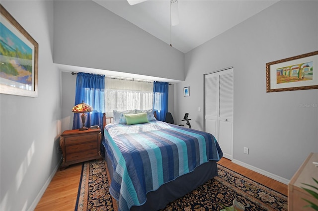 bedroom featuring ceiling fan, high vaulted ceiling, a closet, and light wood-type flooring