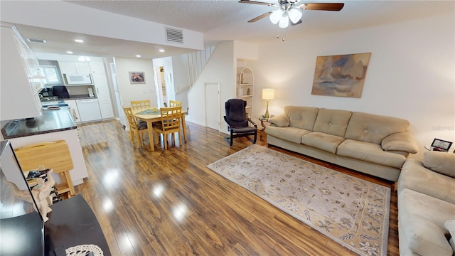 living room featuring ceiling fan, hardwood / wood-style flooring, and a textured ceiling