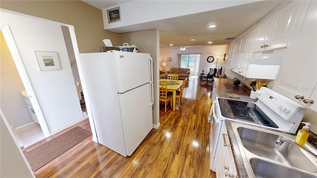 kitchen featuring wood-type flooring, sink, white cabinets, white fridge, and range