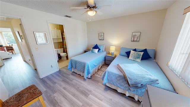 bedroom featuring ceiling fan, connected bathroom, a textured ceiling, and light wood-type flooring