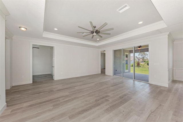 spare room with ornamental molding, light wood-type flooring, ceiling fan, and a tray ceiling