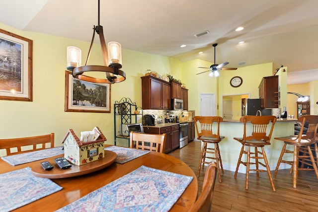 dining room featuring lofted ceiling, ceiling fan with notable chandelier, and dark hardwood / wood-style flooring