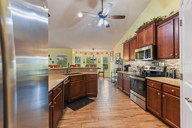 kitchen featuring vaulted ceiling, appliances with stainless steel finishes, pendant lighting, sink, and backsplash