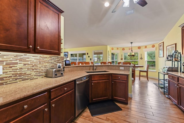 kitchen featuring sink, hanging light fixtures, light wood-type flooring, stainless steel dishwasher, and backsplash