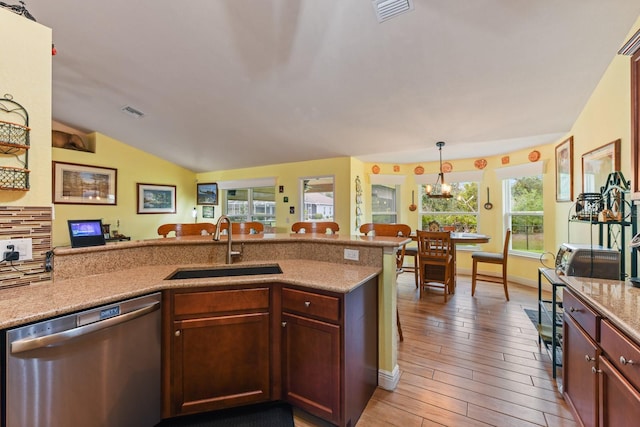 kitchen with sink, dishwasher, dark hardwood / wood-style flooring, decorative light fixtures, and vaulted ceiling