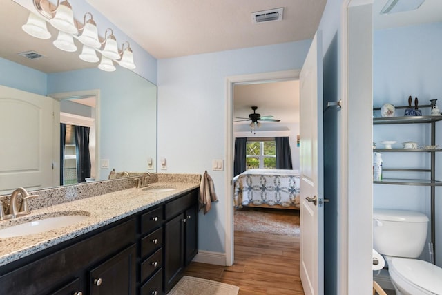 bathroom with wood-type flooring, vanity, ceiling fan, and toilet