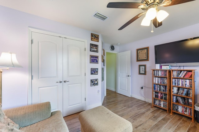 sitting room with ceiling fan and light wood-type flooring