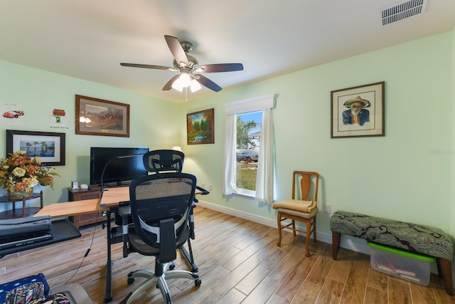 home office with light hardwood / wood-style flooring and ceiling fan