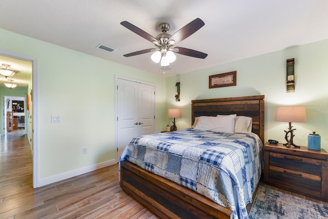 bedroom with light hardwood / wood-style flooring, ceiling fan, and a closet