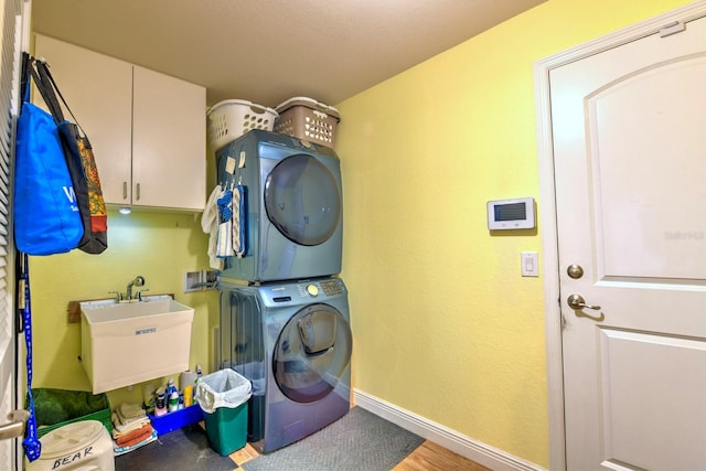 washroom with hardwood / wood-style flooring, cabinets, stacked washing maching and dryer, and sink