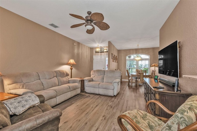 living room with ceiling fan with notable chandelier and hardwood / wood-style floors