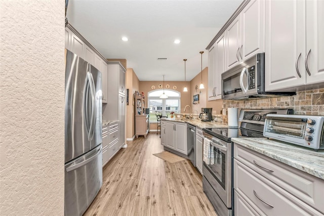 kitchen with light stone countertops, appliances with stainless steel finishes, gray cabinetry, and decorative light fixtures