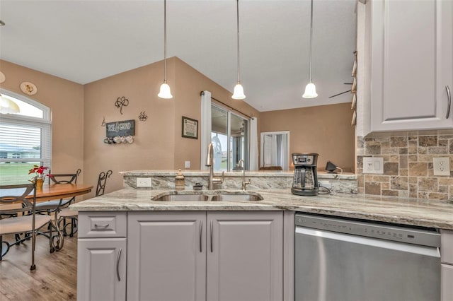 kitchen with white cabinetry, sink, hanging light fixtures, stainless steel dishwasher, and light wood-type flooring