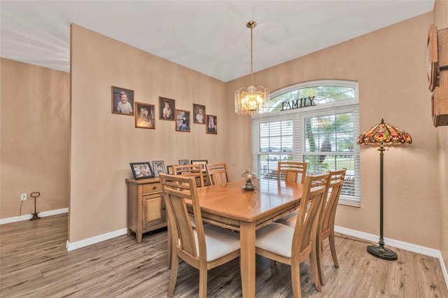 dining area with an inviting chandelier and light hardwood / wood-style flooring