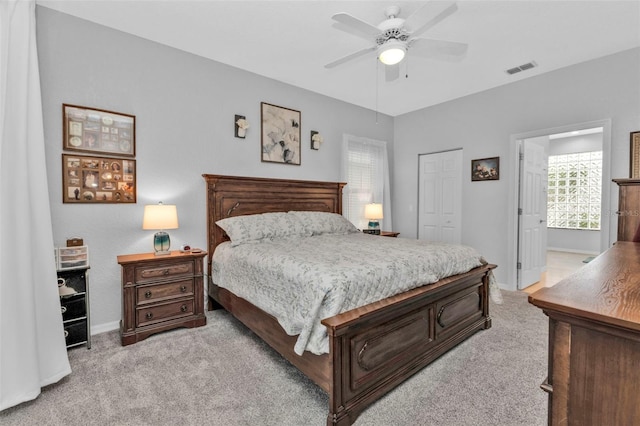 bedroom with light carpet, ensuite bath, a closet, and ceiling fan