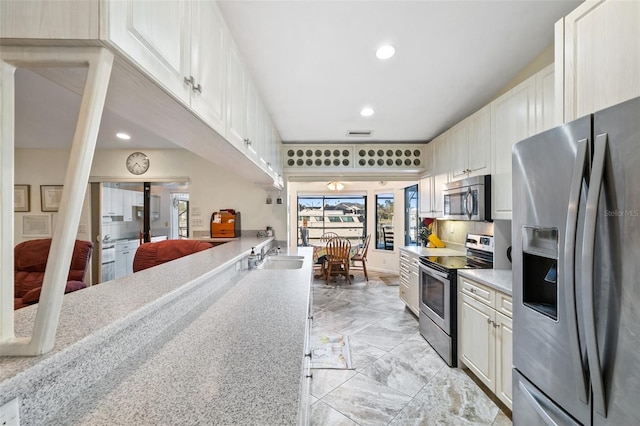 kitchen featuring white cabinetry, stainless steel appliances, sink, and light stone counters