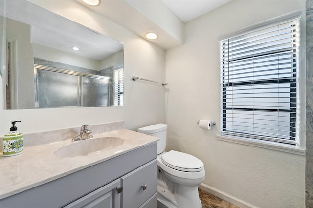 bathroom featuring vanity, toilet, and a shower with door