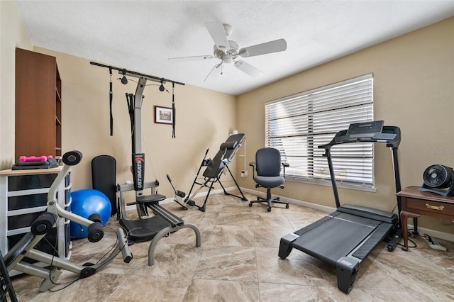 workout room with ceiling fan and a textured ceiling