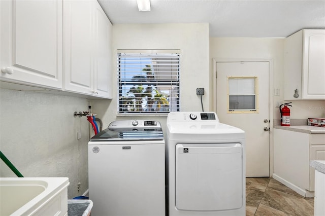 clothes washing area with cabinets and washing machine and clothes dryer