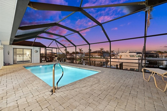 pool at dusk featuring a lanai, a dock, and a patio area