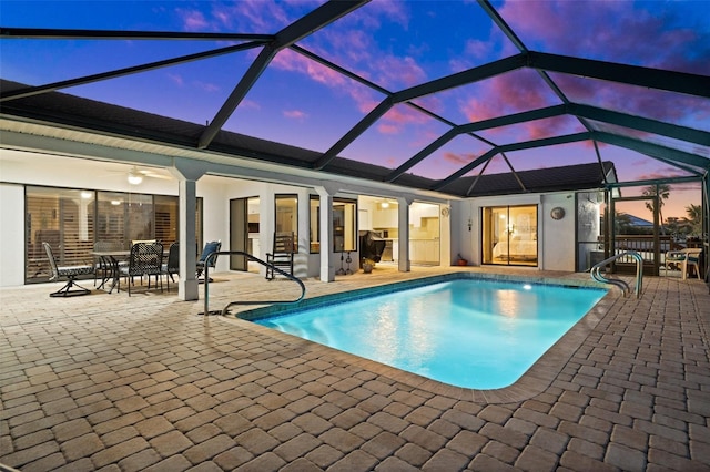 pool at dusk with a patio and glass enclosure