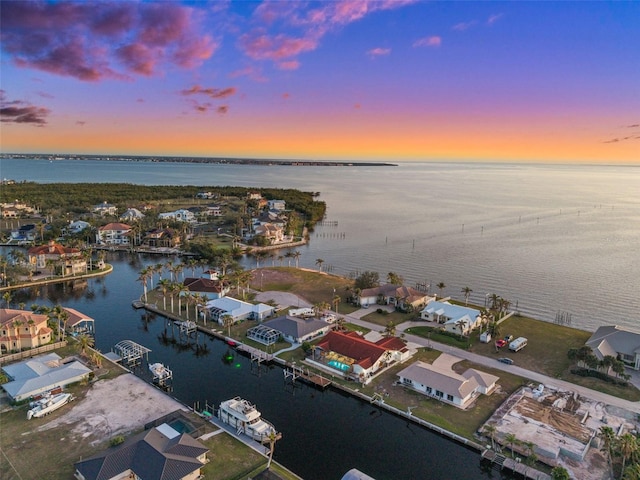 aerial view at dusk featuring a water view