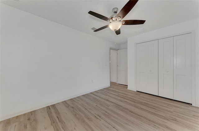 unfurnished bedroom featuring ceiling fan, light hardwood / wood-style floors, and a closet