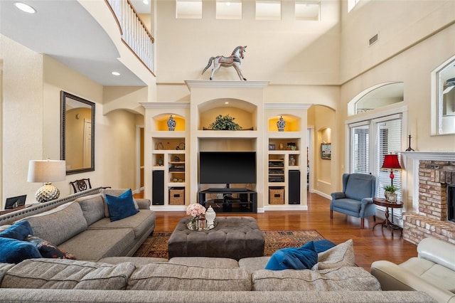 living room featuring a brick fireplace, dark wood-type flooring, and built in features