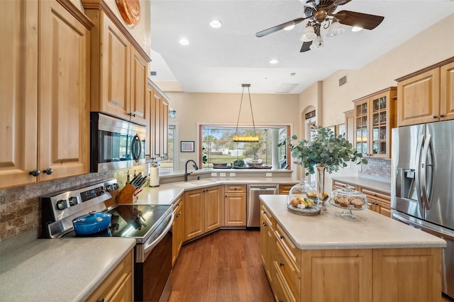 kitchen featuring dark wood-type flooring, sink, hanging light fixtures, appliances with stainless steel finishes, and decorative backsplash