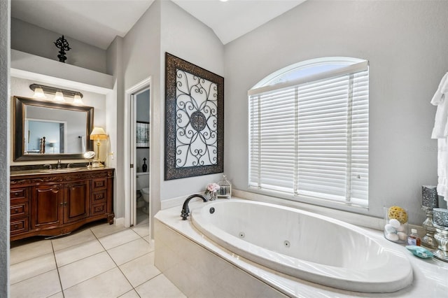 bathroom with tile patterned flooring, vanity, tiled bath, and toilet